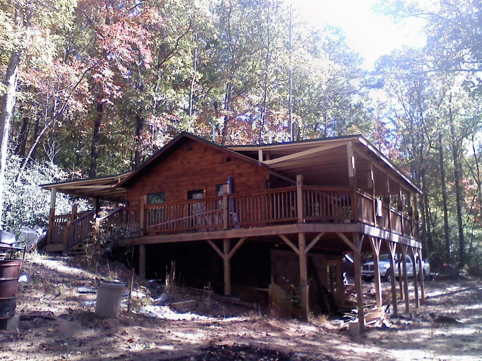 Log cabin with a wraparound porch and metal roof in the fall in Oxford